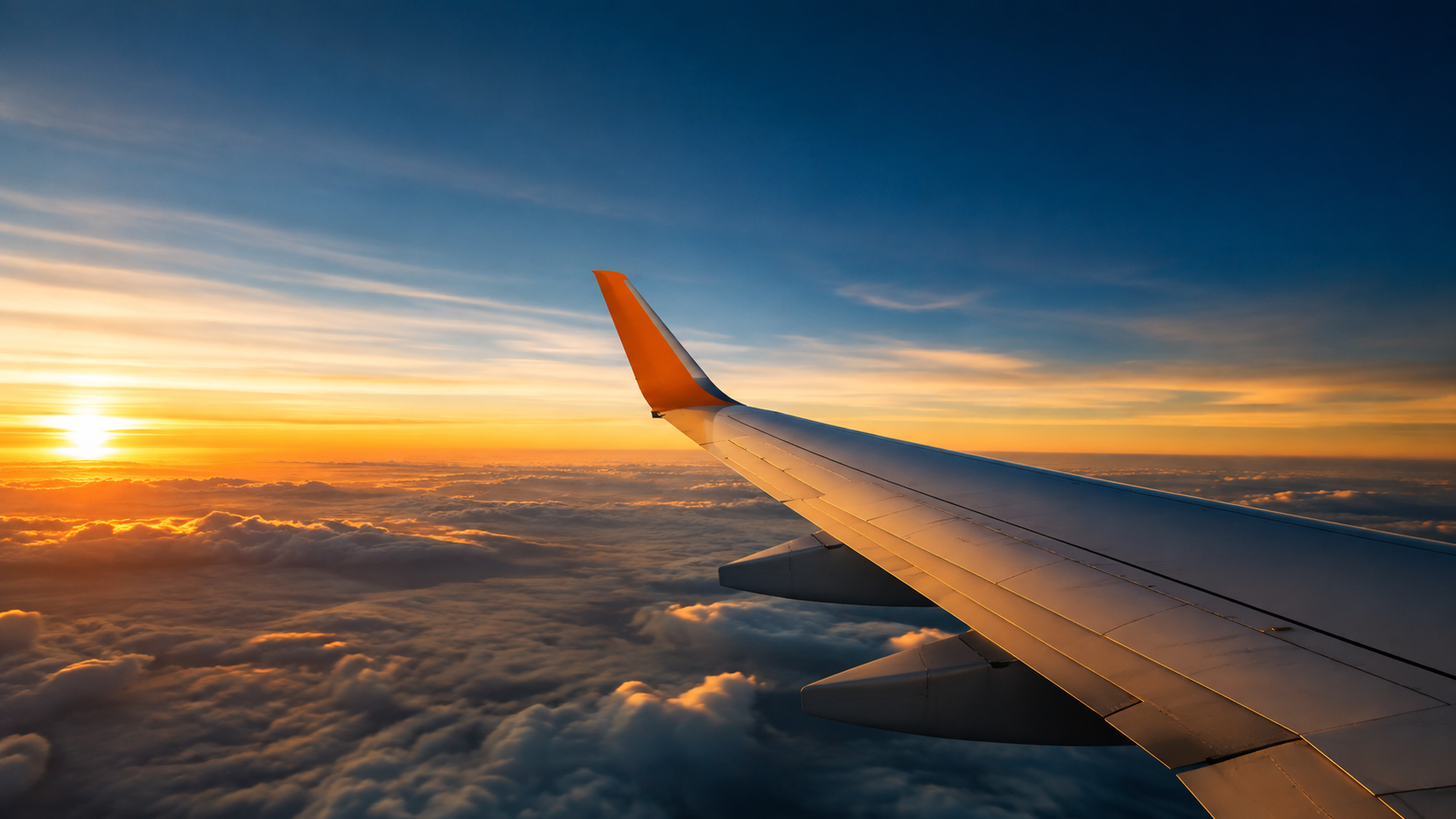 Vista da asa de um avião ao pôr do sol acima das nuvens